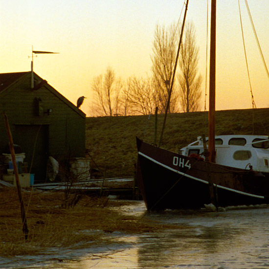 Zoom: De boot van Doets te Schardam in het ijs, met kleumende reiger in het licht van de ondergaande zon