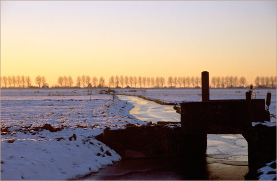 Een bruggetje in de Kleine Waterling van de Beetskoog bij een winterse zonsondergang, van dichtbij