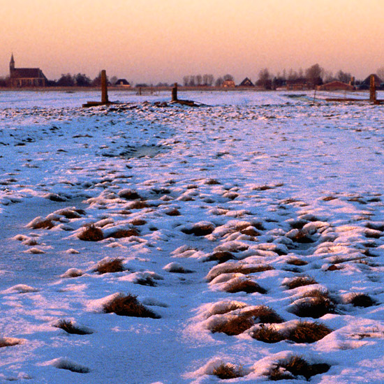 De Beetskoog onder sneeuw en ijs bij zonsondergang, met Oudendijk op de achtergrond