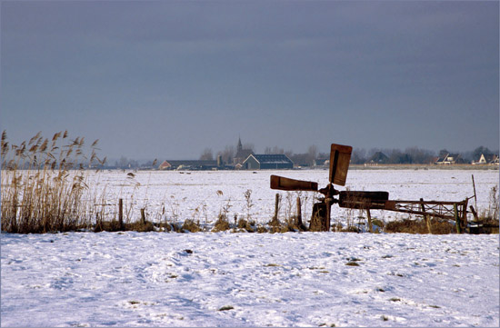 Zieltogend molentje in de sneeuw van de Beetskoog, met Oudendijk in de achtergrond