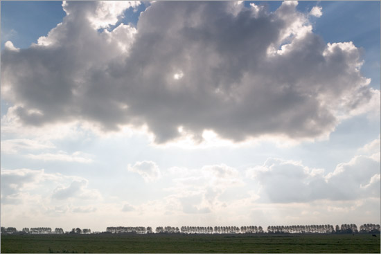 Wolk boven de Beetskoog en verblindend oktoberlicht achter de populieren op de Beemsterdijk