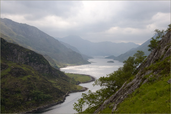 Looking down on Skiary from the climb to Cadha Mhòr; bright sun breaks through dark clouds, lighting up Loch Hourn