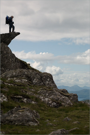 Elderly gentleman with rucksack and camerabag watching evening clouds from Meall nan Eun